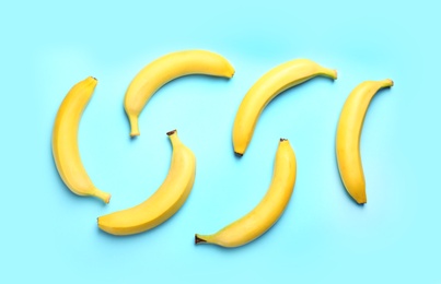 Ripe tasty bananas on blue background, flat lay