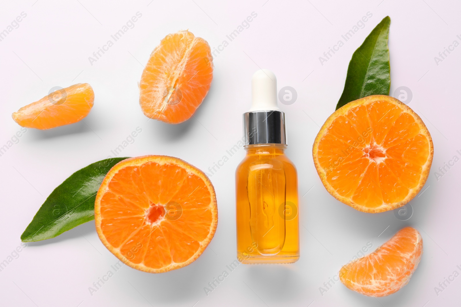 Photo of Aromatic tangerine essential oil in bottle, leaves and citrus fruits on white table, flat lay