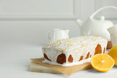 Photo of Tasty lemon cake with glaze and citrus fruits on white wooden table. Space for text