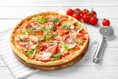 Photo of Tasty hot pizza, cherry tomatoes and knife on wooden background