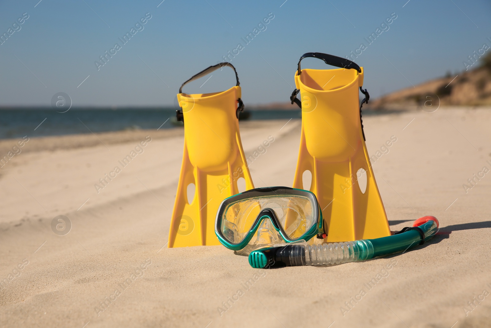 Photo of Pair of flippers, snorkel and diving mask on sandy beach