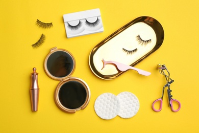 Flat lay composition with magnetic eyelashes and accessories on yellow background