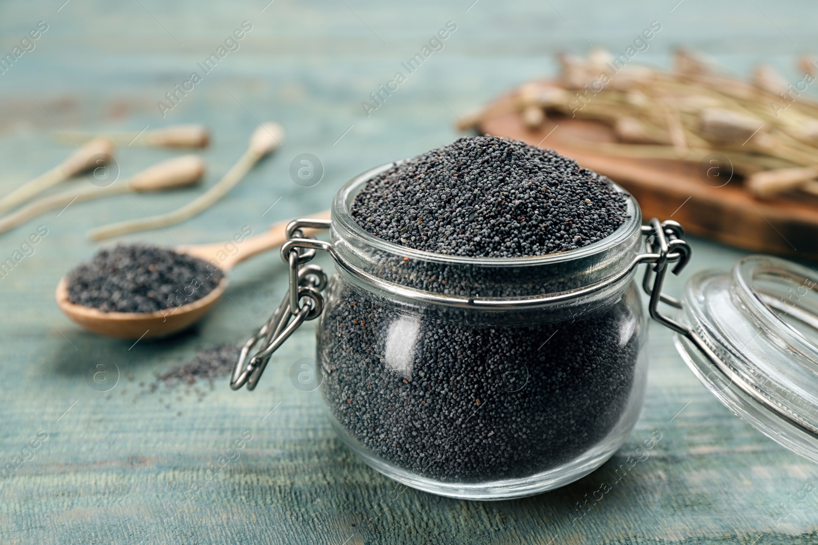 Photo of Poppy seeds in glass jar on blue wooden table