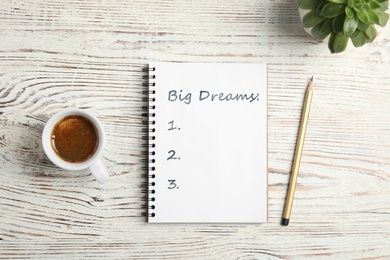 Image of Notebook with dreams list on white wooden table, flat lay 