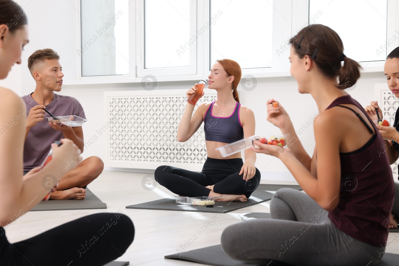 Photo of Group of people eating healthy food after yoga class indoors