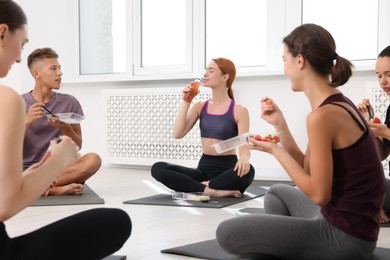 Photo of Group of people eating healthy food after yoga class indoors