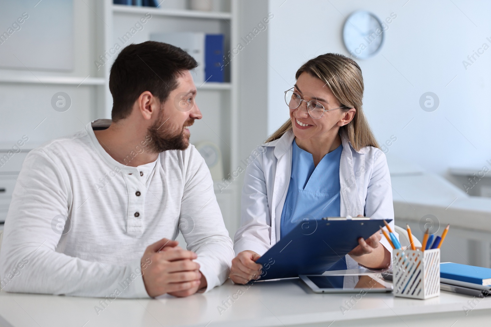 Photo of Professional doctor working with patient at white table in hospital