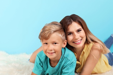 Photo of Mother and son lying on fuzzy rug near color wall