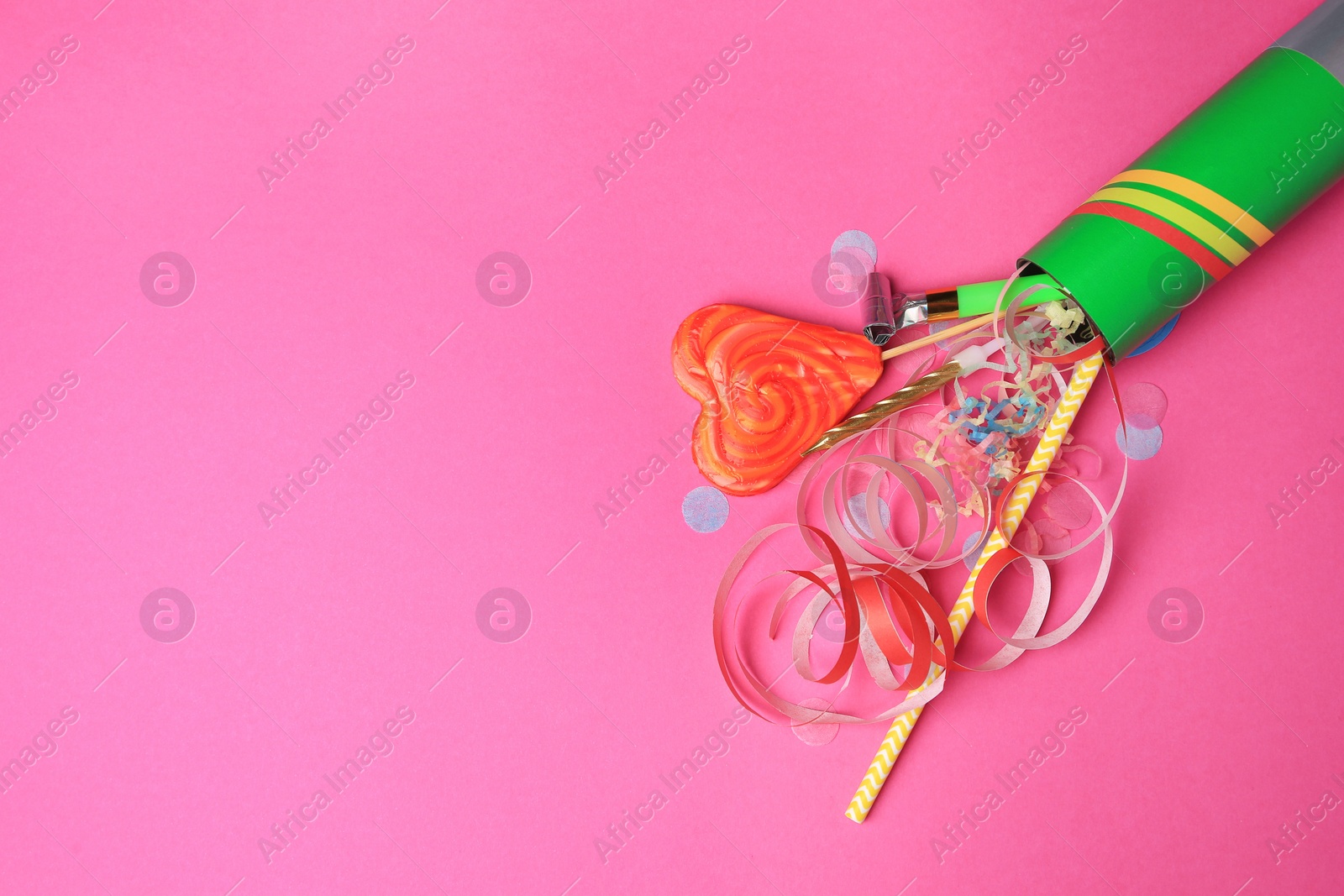 Photo of Party cracker and different festive items on bright pink background, flat lay. Space for text