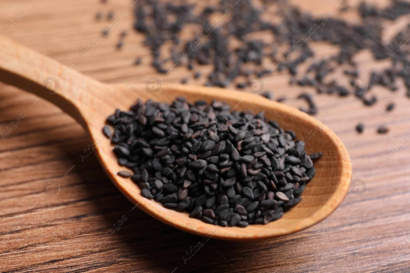 Photo of Black sesame seeds on wooden table, closeup