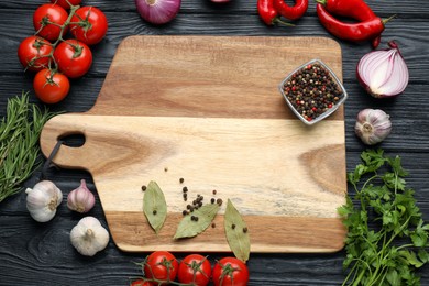 Photo of Cutting board and vegetables on black wooden table, flat lay. Cooking utensil