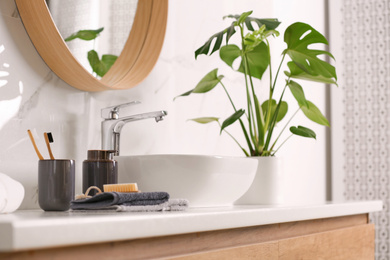 Toiletries and stylish vessel sink on light countertop in modern bathroom