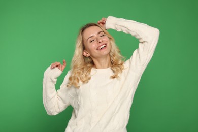 Happy woman in stylish warm sweater on green background