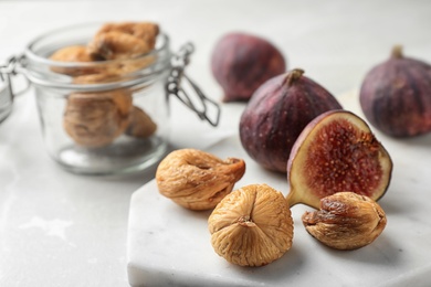 Photo of Marble board with dried and raw figs on light table, closeup. Space for text