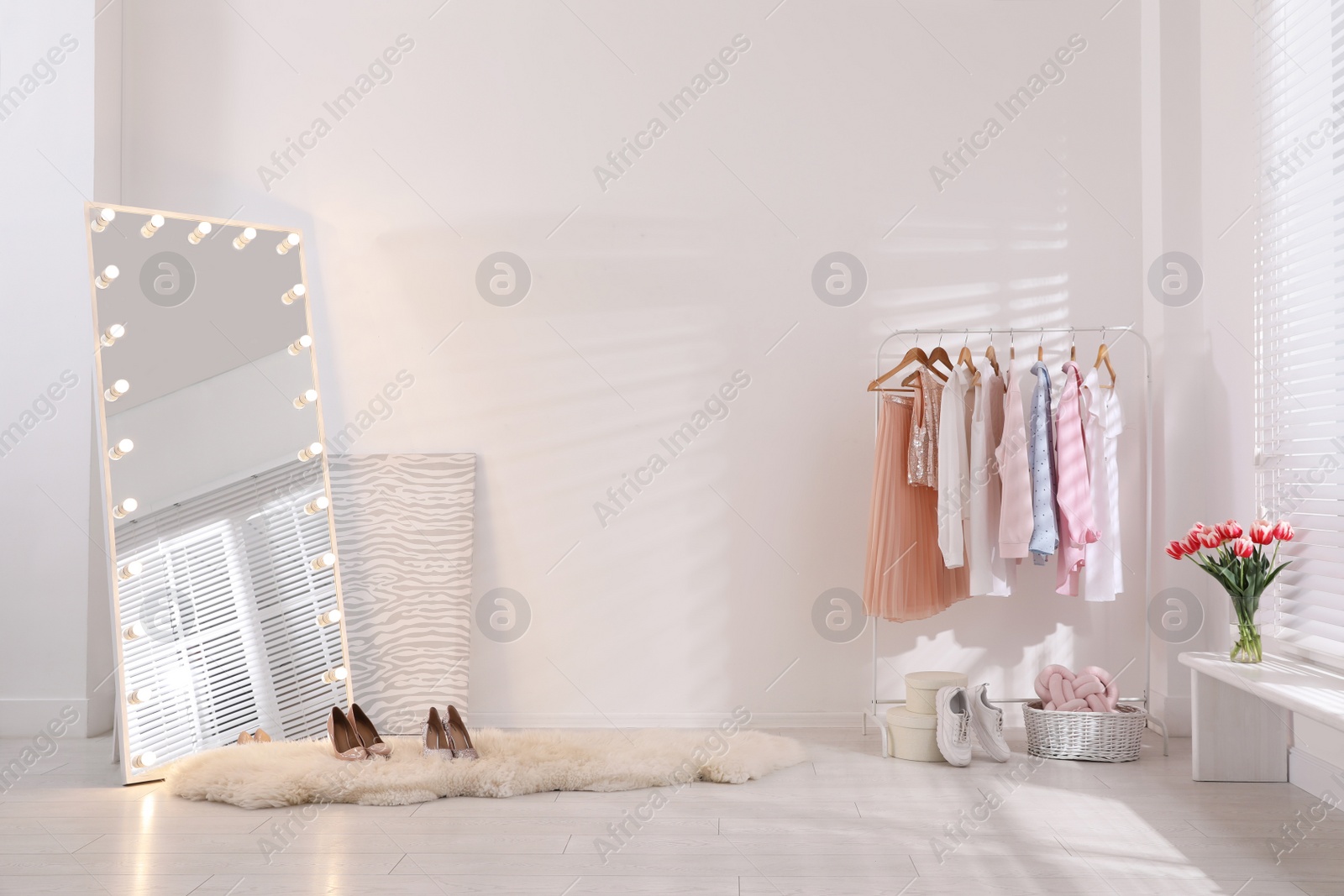 Photo of Rack with stylish women's clothes and mirror indoors. Interior design