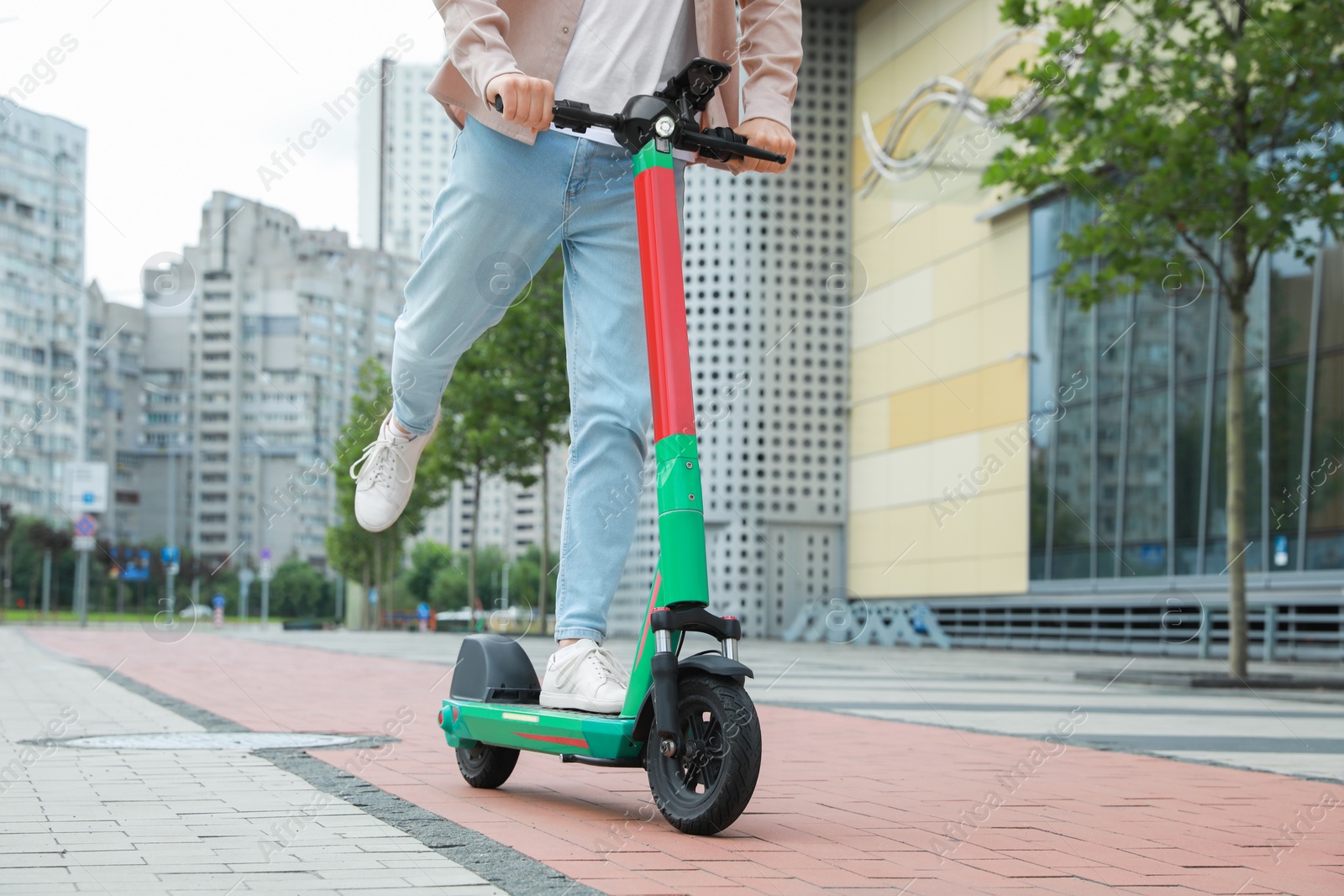 Photo of Man riding modern electric kick scooter on city street, closeup