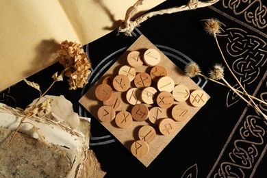 Photo of Many wooden runes, old books and dried flowers on divination mat, flat lay