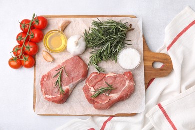 Photo of Fresh raw meat with rosemary, oil, tomatoes and spices on light table, flat lay