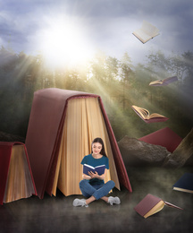 Young woman reading and flying books in foggy forest on sunny day