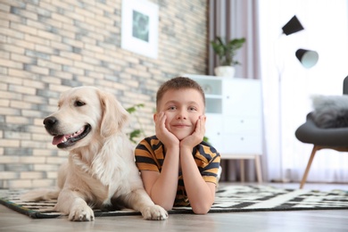 Photo of Cute little child with his pet on floor at home