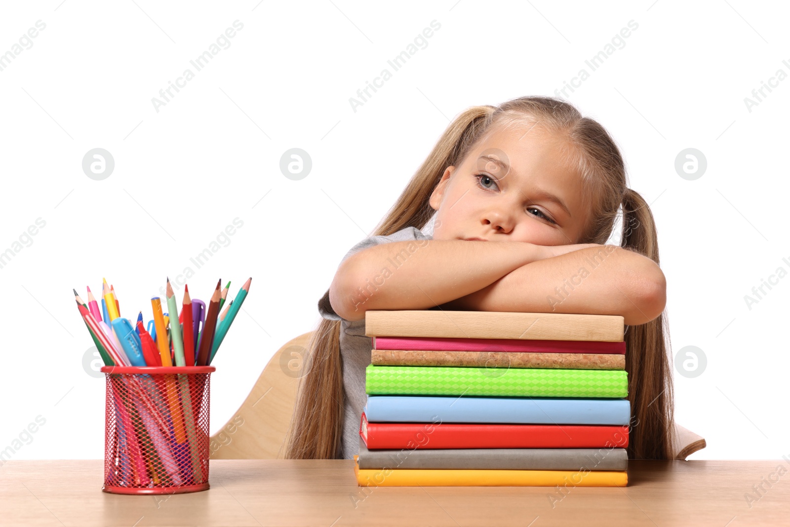 Photo of Little girl with stationery and stack of books suffering from dyslexia at wooden table