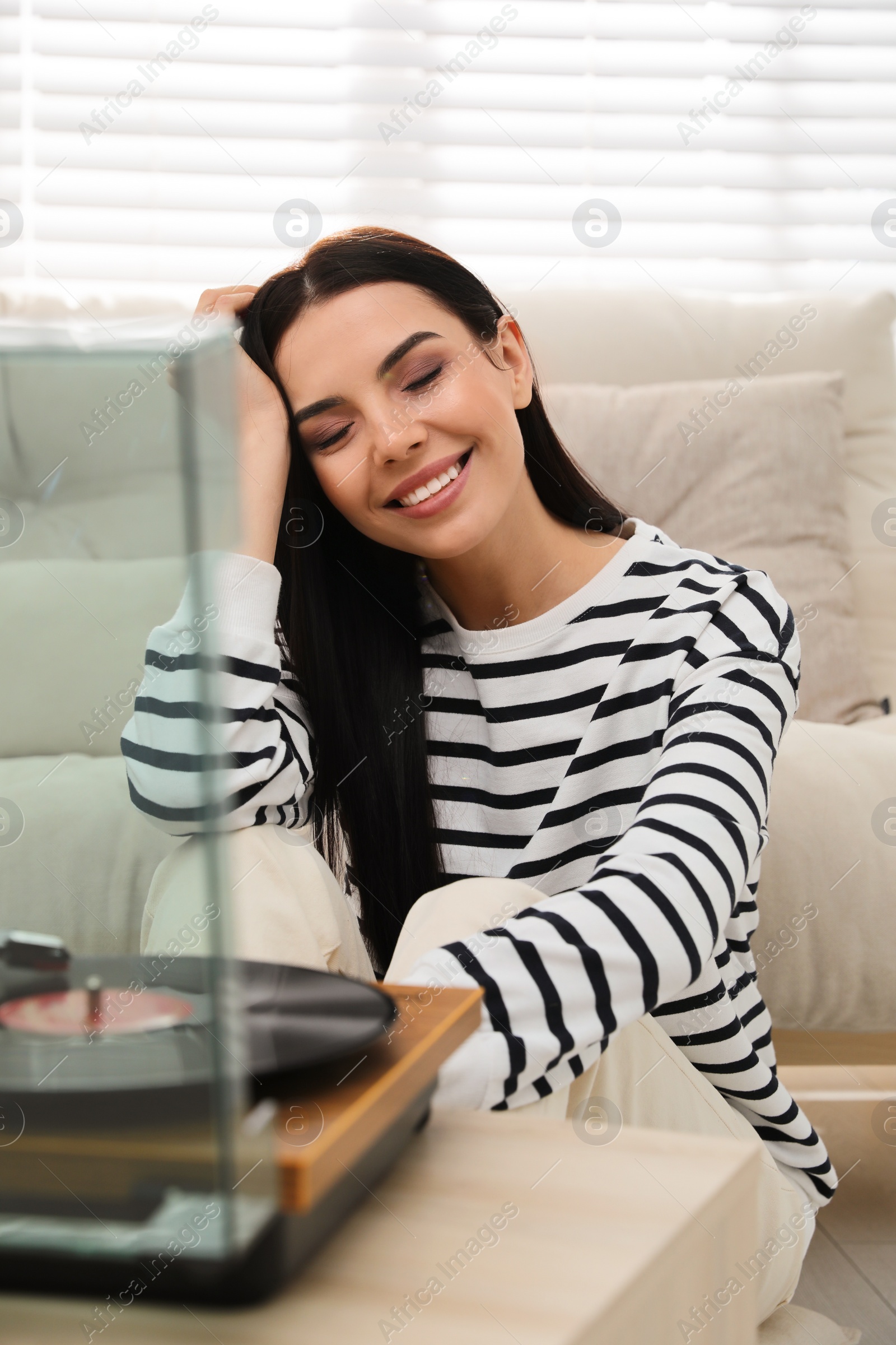 Photo of Woman listening to music with turntable at home