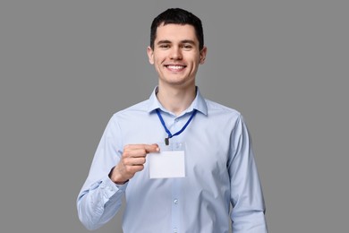 Photo of Smiling man showing empty badge on grey background