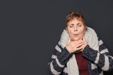 Elderly woman coughing against dark background. Space for text