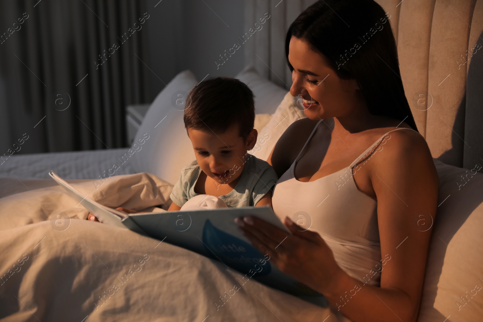 Photo of Mother reading bedtime story to her son at home