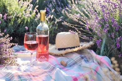 Bottle and glass of wine on blanket in lavender field