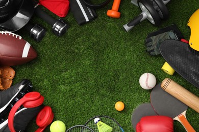 Photo of Frame of different sports equipment on green grass, flat lay. Space for text