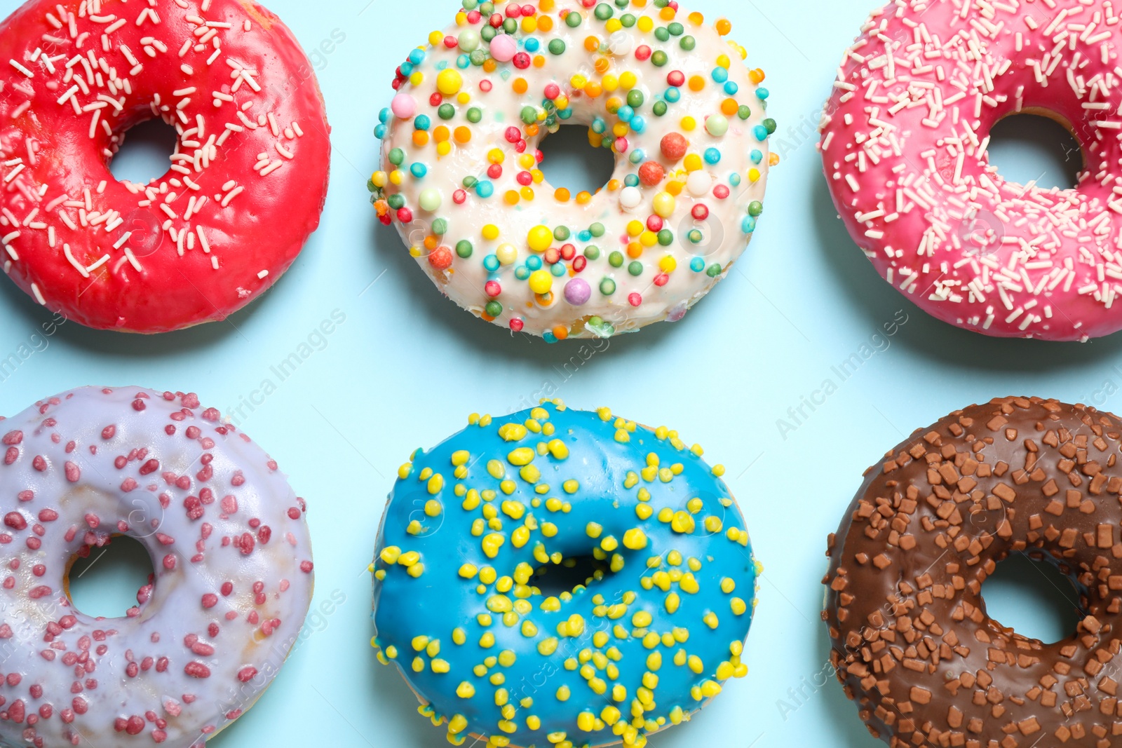 Photo of Delicious glazed donuts on light blue background, flat lay