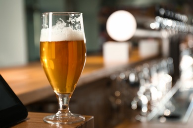 Photo of Glass of beer on wooden counter in pub. Space for text