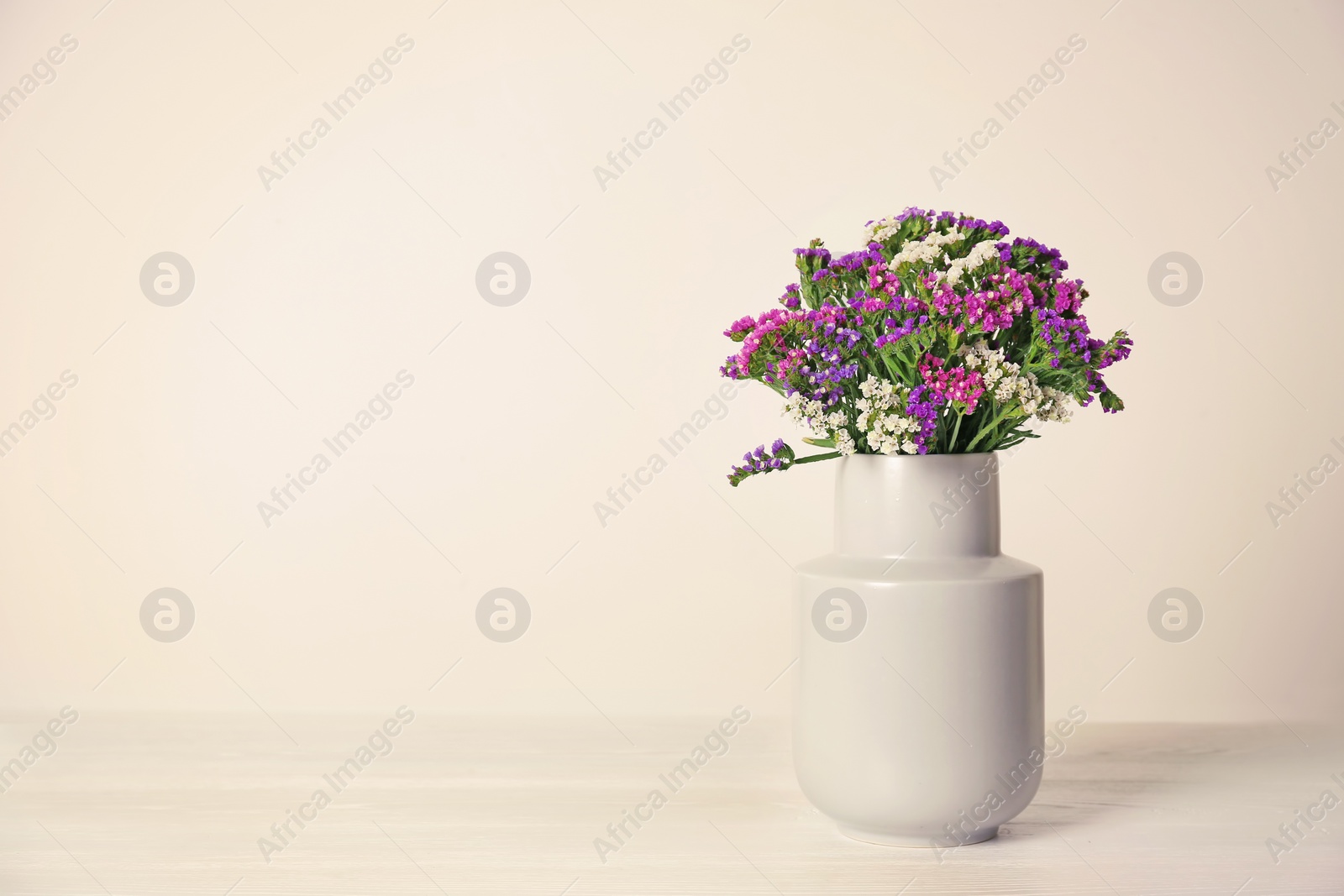 Photo of Beautiful flowers in vase and space for text on light background. Element of interior design