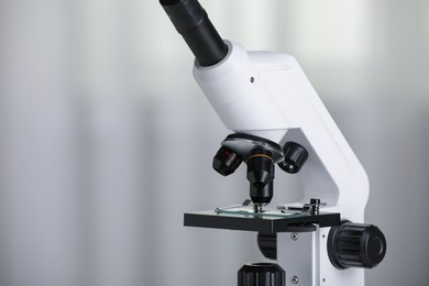 Photo of Modern microscope on light background, closeup. Space for text