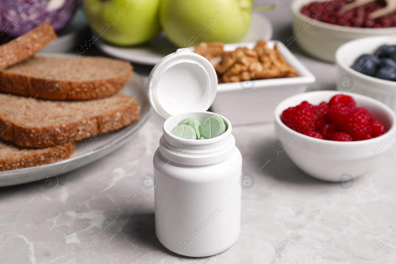 Photo of Bottle of pills near foodstuff on grey table. Prebiotic supplements