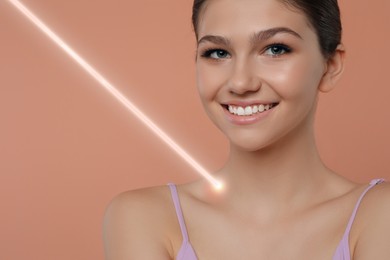 Laser mole removal. Teenage girl with ray pointed at her skin during procedure on pale coral background. Space for text