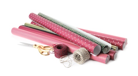 Photo of Different colorful wrapping paper rolls, scissors and ropes on white background