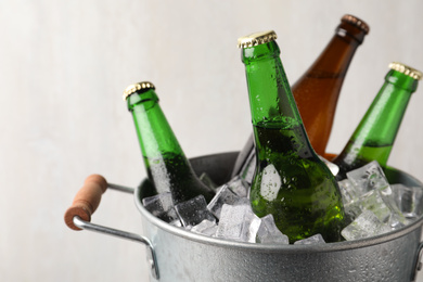 Photo of Metal bucket with bottles of beer and ice cubes on grey background