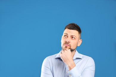 Photo of Thoughtful man on blue background, space for text