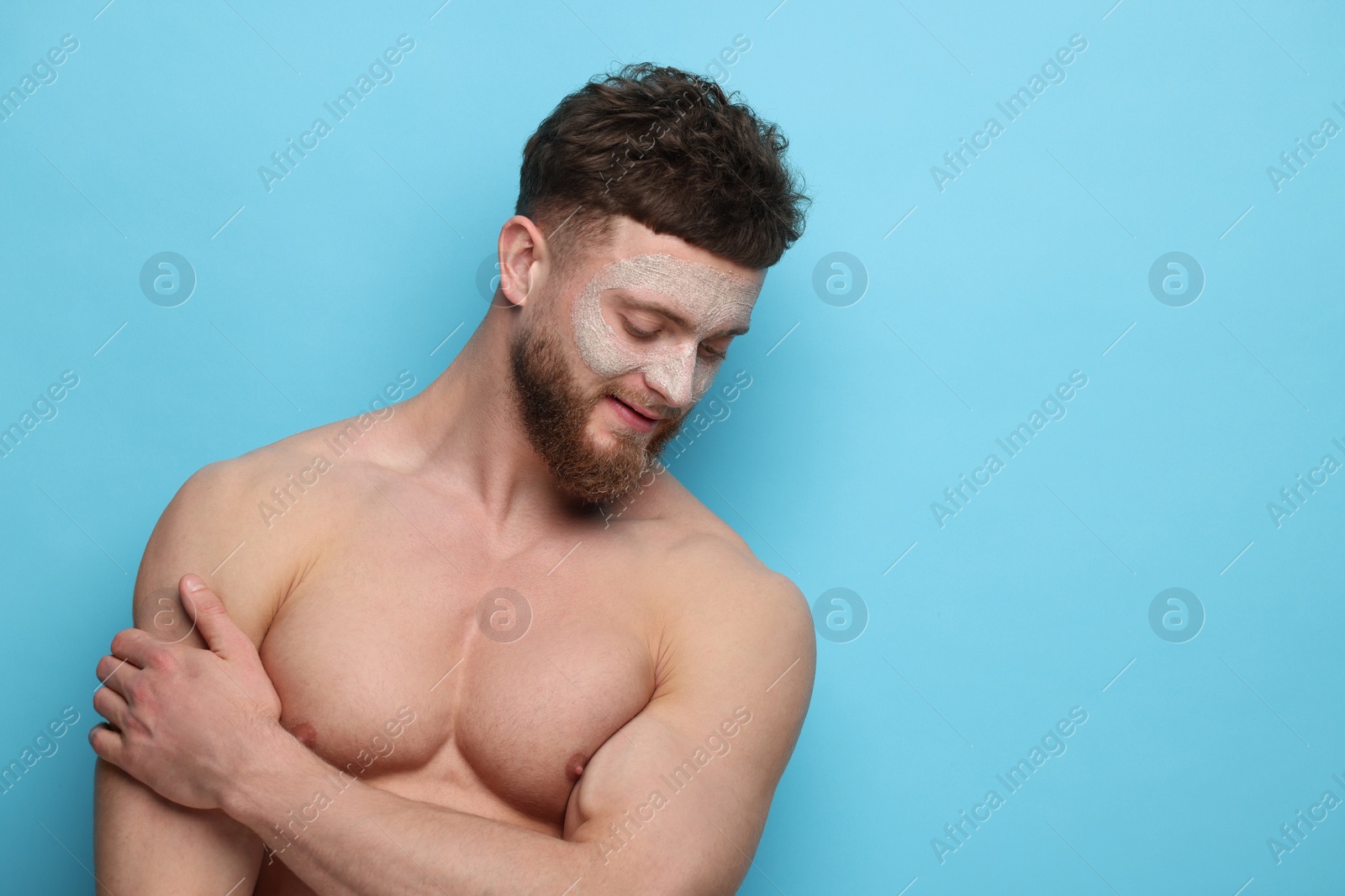 Photo of Handsome man with facial mask on his face against light blue background, space for text