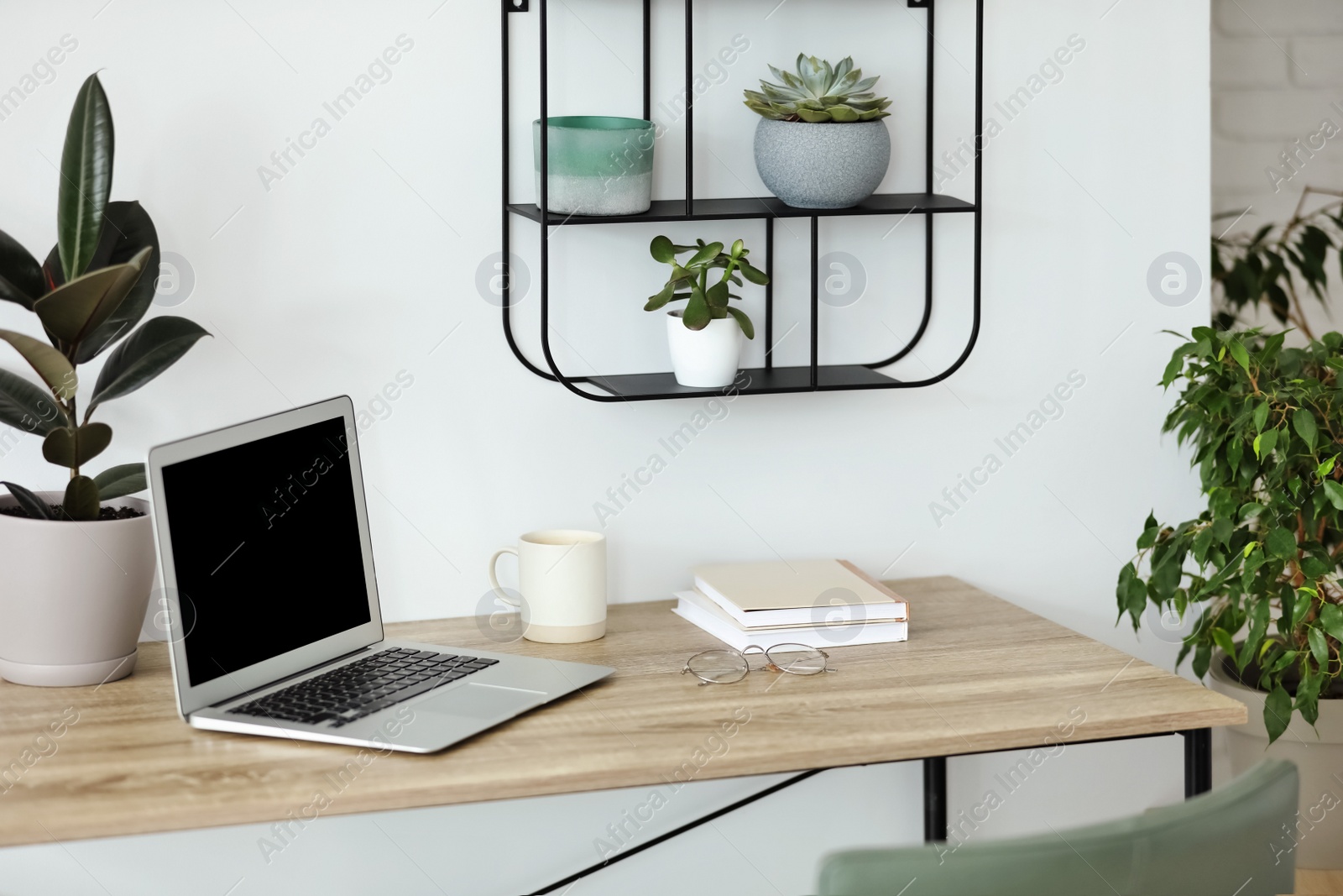 Photo of Comfortable workplace with modern laptop on wooden table in room. Interior design