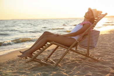 Photo of Young woman relaxing in deck chair on beach