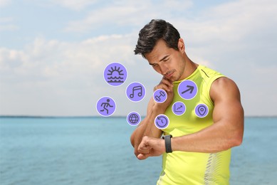 Young man checking fitness tracker after training on beach