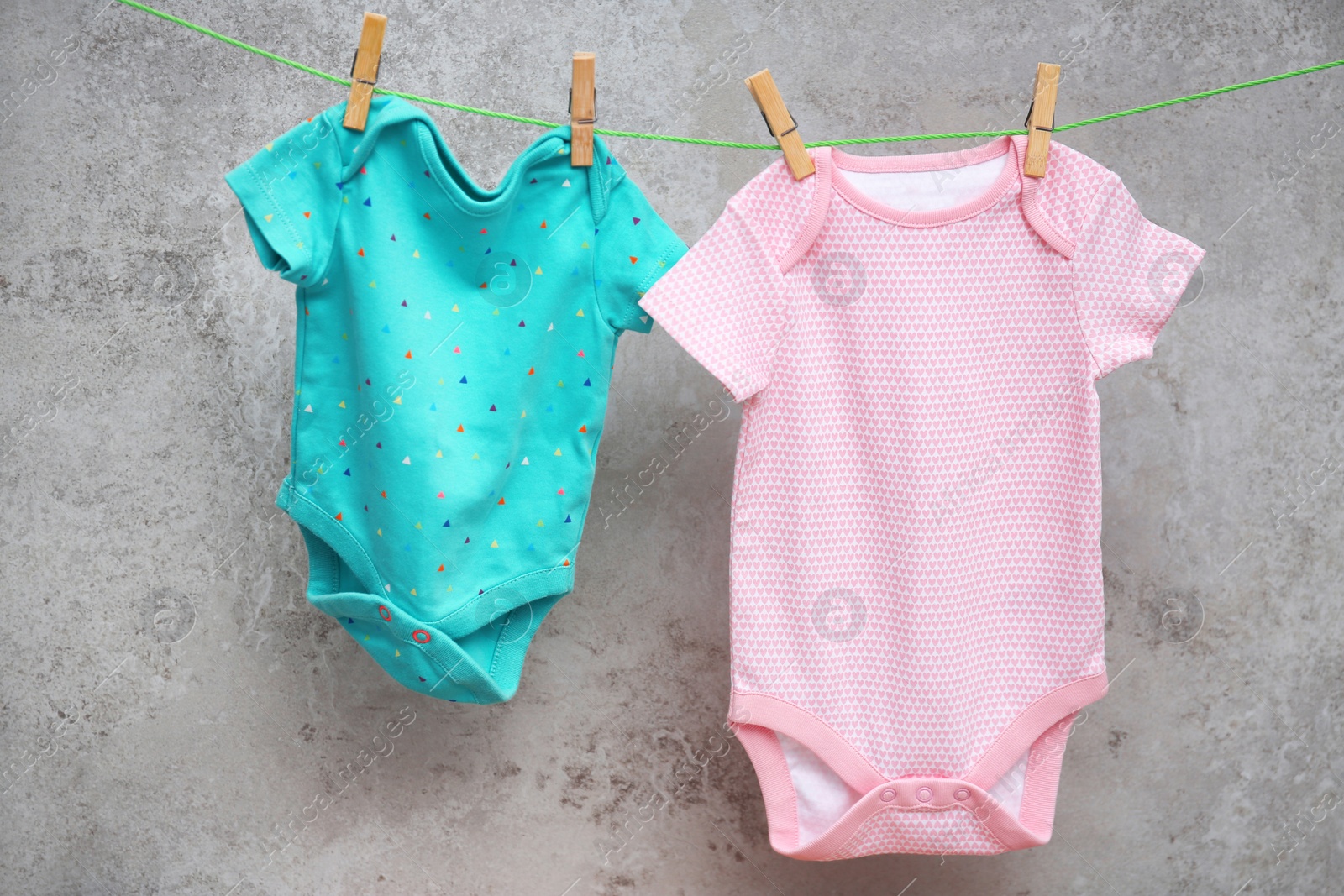 Photo of Baby clothes hanging on washing line against gray background