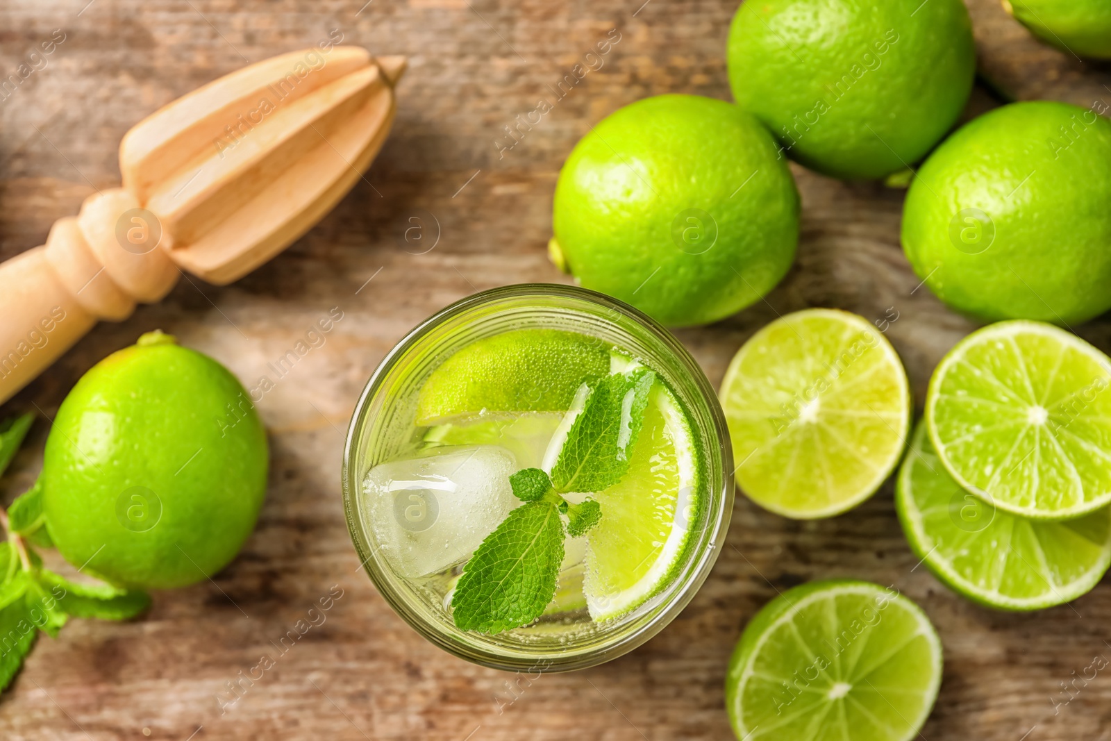 Photo of Refreshing lime beverage and ingredients on wooden background, top view