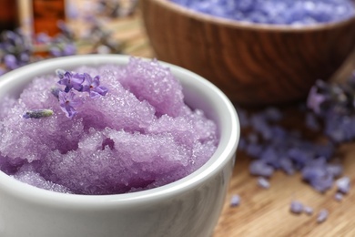 Bowl of natural sugar scrub and lavender flowers on table, closeup. Space for text