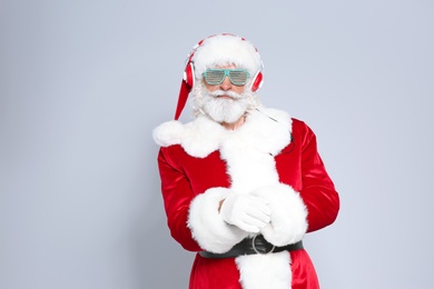 Photo of Santa Claus listening to Christmas music on color background