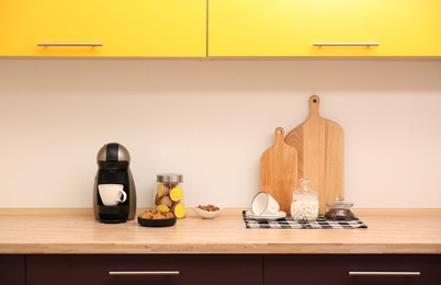 Modern coffeemaker on countertop near light wall in kitchen