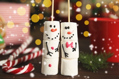 Funny snowmen made of marshmallows on wooden table, closeup